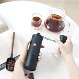 En person som maler färska kaffebönor med en Timemore C5 Pro kaffekvarn i ett kök